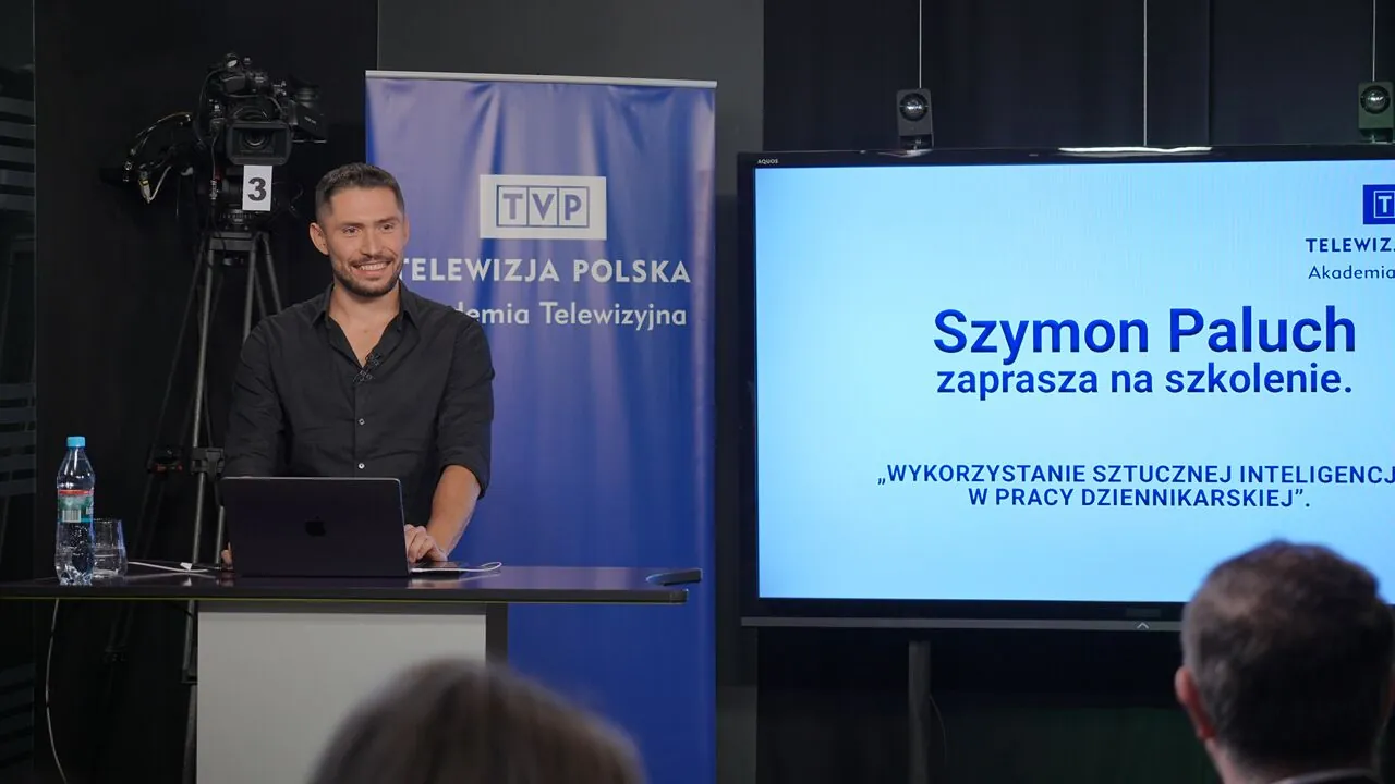 Szymon Paluch running a training session in a TVP studio: the Television Academy roll-up, studio cameras, a lectern with a laptop and a screen showing the session title